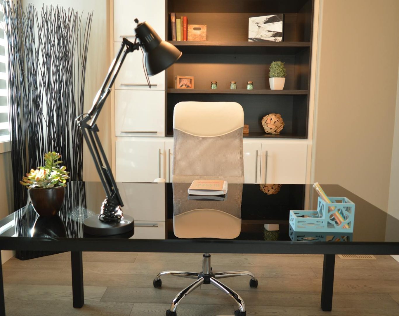 Stylish modern office workspace featuring a black desk, lamp, and white chair with shelving.