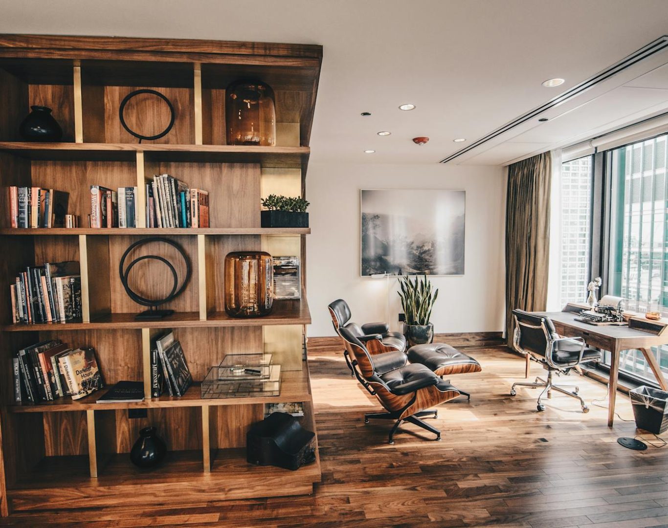 Stylish office space featuring a wooden bookshelf and a minimalist desk setup, ideal for work.