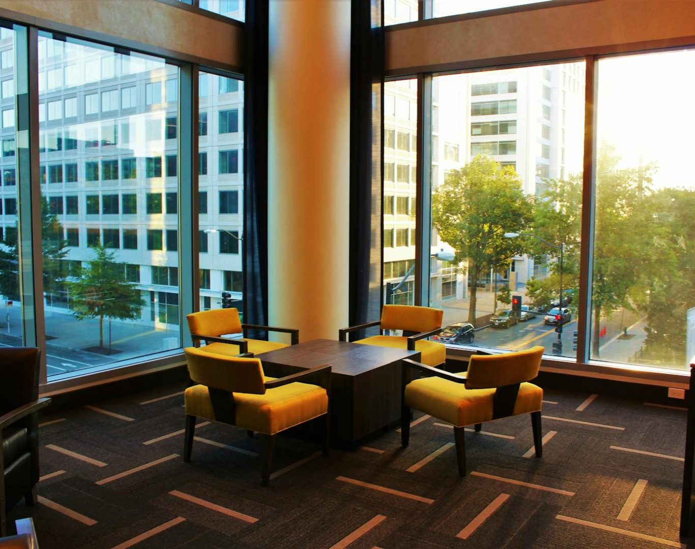 Contemporary hotel lounge featuring yellow chairs and cityscape view through large windows.